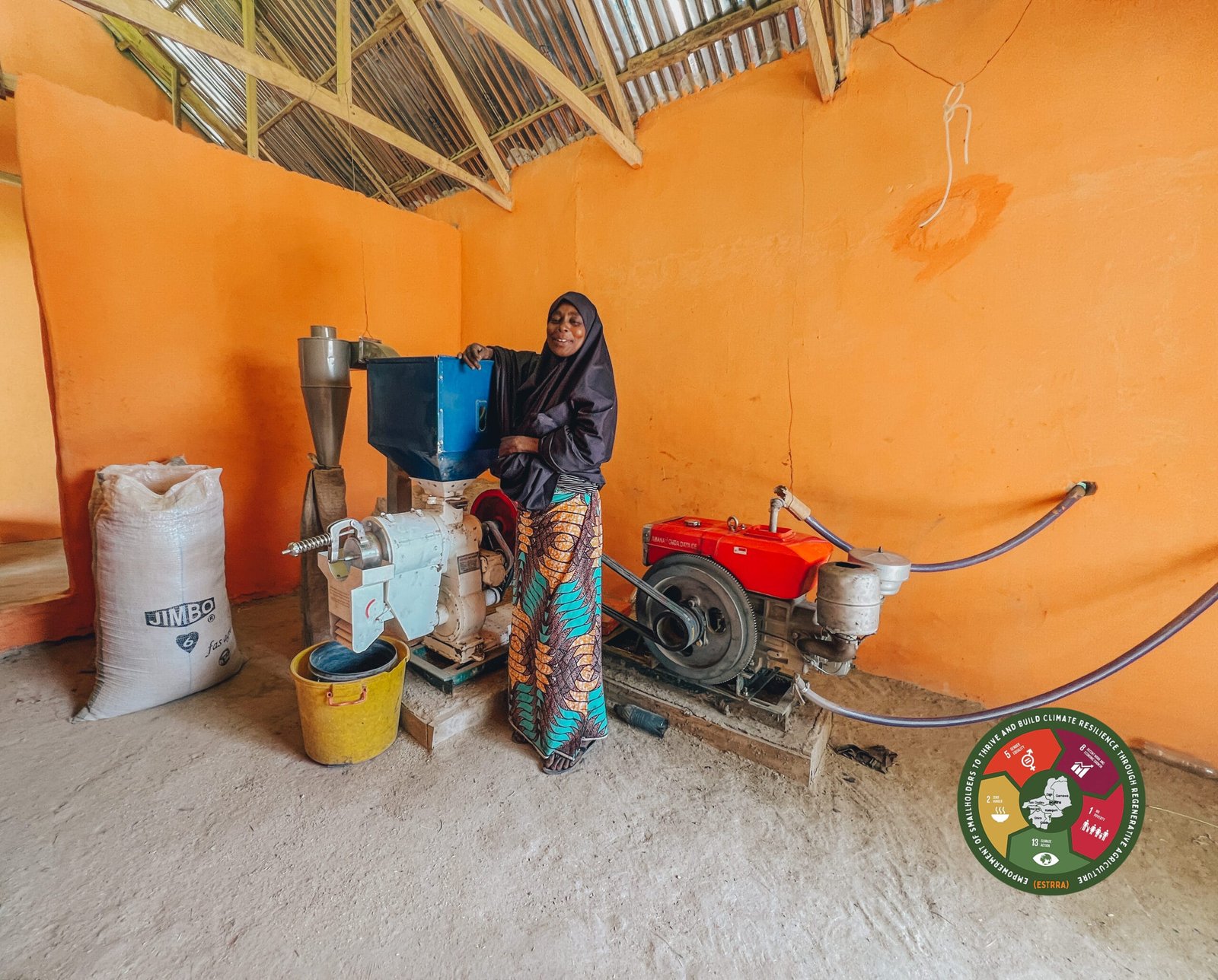Altine Lamara standing beside the rice milling engine provided for her through the ESTRRA project