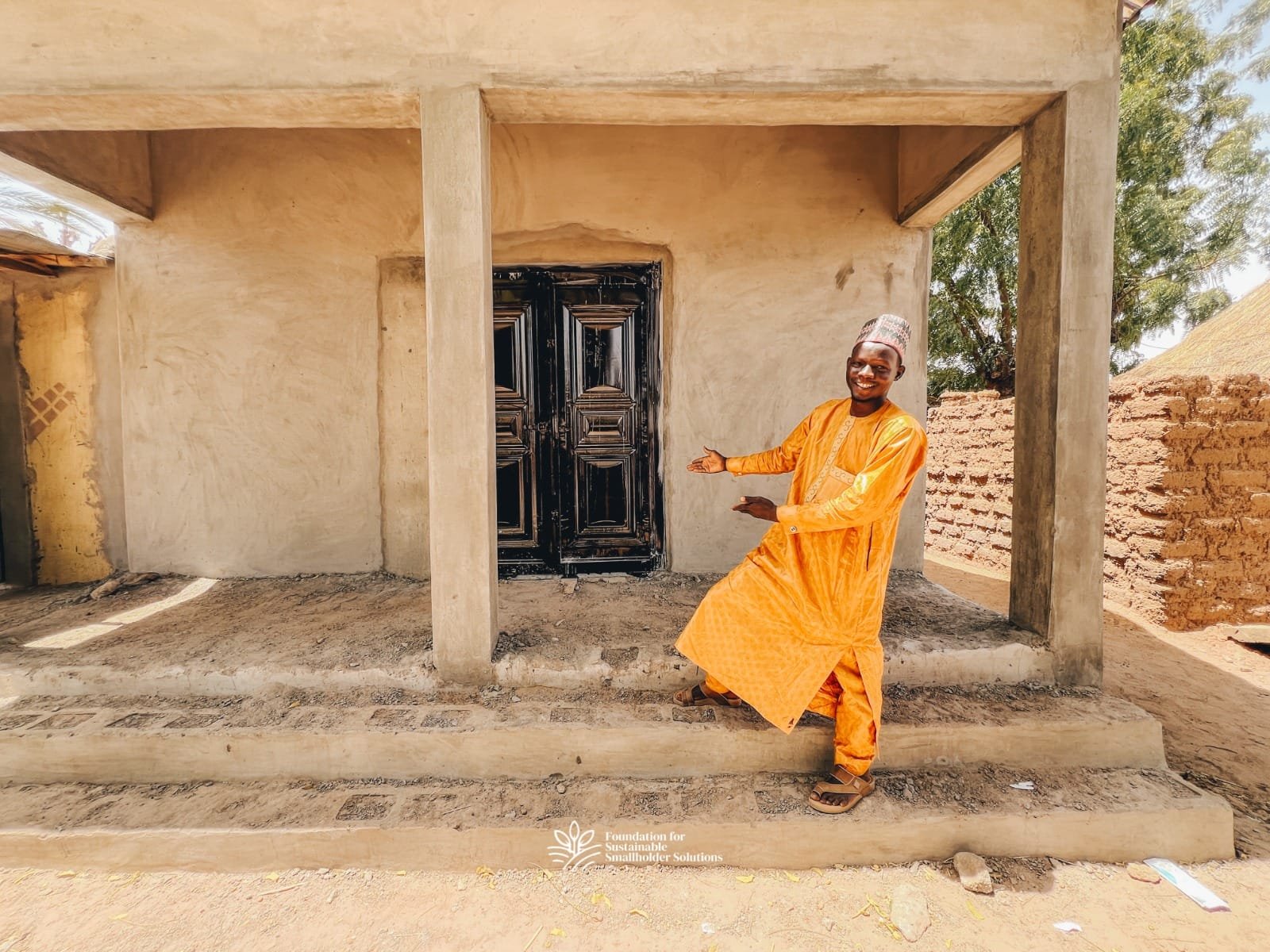 Sabiu Adamu posing with a smile in front of his Farmers' Hub while still under construction